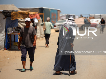 Displaced Palestinians are walking next to a temporary camp in Khan Yunis, south of the Gaza Strip, on July 4, 2024, amid the ongoing confli...