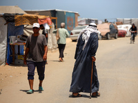 Displaced Palestinians are walking next to a temporary camp in Khan Yunis, south of the Gaza Strip, on July 4, 2024, amid the ongoing confli...