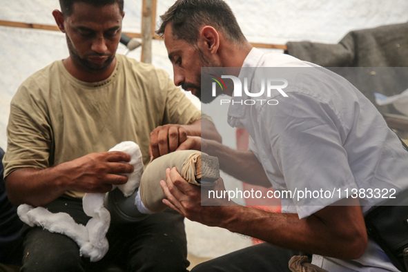 Muattaz Abu Dayeh, a physiotherapist, is applying a medical prosthesis to 32-year-old worker Majd al-Omari, who lost part of his leg during...