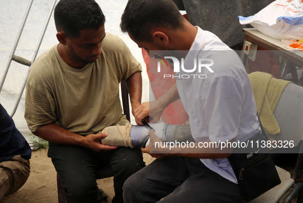 Muattaz Abu Dayeh, a physiotherapist, is applying a medical prosthesis to 32-year-old worker Majd al-Omari, who lost part of his leg during...