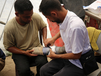 Muattaz Abu Dayeh, a physiotherapist, is applying a medical prosthesis to 32-year-old worker Majd al-Omari, who lost part of his leg during...