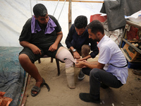 Muattaz Abu Dayeh, a physiotherapist, is applying a medical prosthesis to 32-year-old worker Majd al-Omari, who is losing part of his leg du...