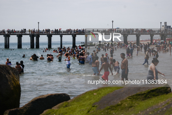 A view on Pat Auletta Steeplechase Pier and crowds of people enjoying the beach at Coney Island Beach on Independence Day in New York, Unite...