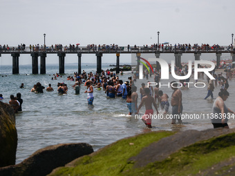 A view on Pat Auletta Steeplechase Pier and crowds of people enjoying the beach at Coney Island Beach on Independence Day in New York, Unite...