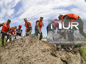 Armed police officers and soldiers are filling sandbags for flood control at the Changjiang River embankment section of Rixin village, Mianc...