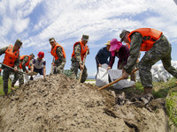 Armed police officers and soldiers are filling sandbags for flood control at the Changjiang River embankment section of Rixin village, Mianc...