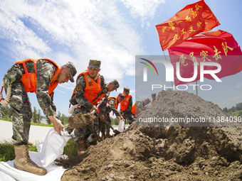 Armed police officers and soldiers are filling sandbags for flood control at the Changjiang River embankment section of Rixin village, Mianc...