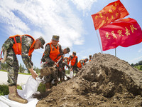 Armed police officers and soldiers are filling sandbags for flood control at the Changjiang River embankment section of Rixin village, Mianc...