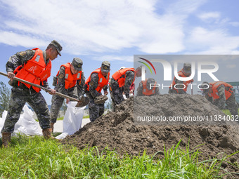 Armed police officers and soldiers are filling sandbags for flood control at the Changjiang River embankment section of Rixin village, Mianc...