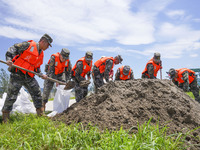 Armed police officers and soldiers are filling sandbags for flood control at the Changjiang River embankment section of Rixin village, Mianc...