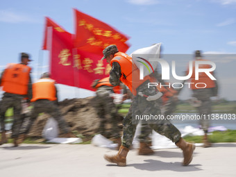 Armed police officers and soldiers are filling sandbags for flood control at the Changjiang River embankment section of Rixin village, Mianc...