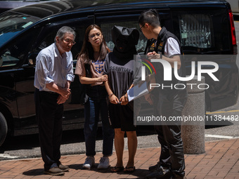 Police officers are escorting a suspect involved in a kidnapping case wearing a head cover to a police reenactment in Hong Kong, on July 4,...