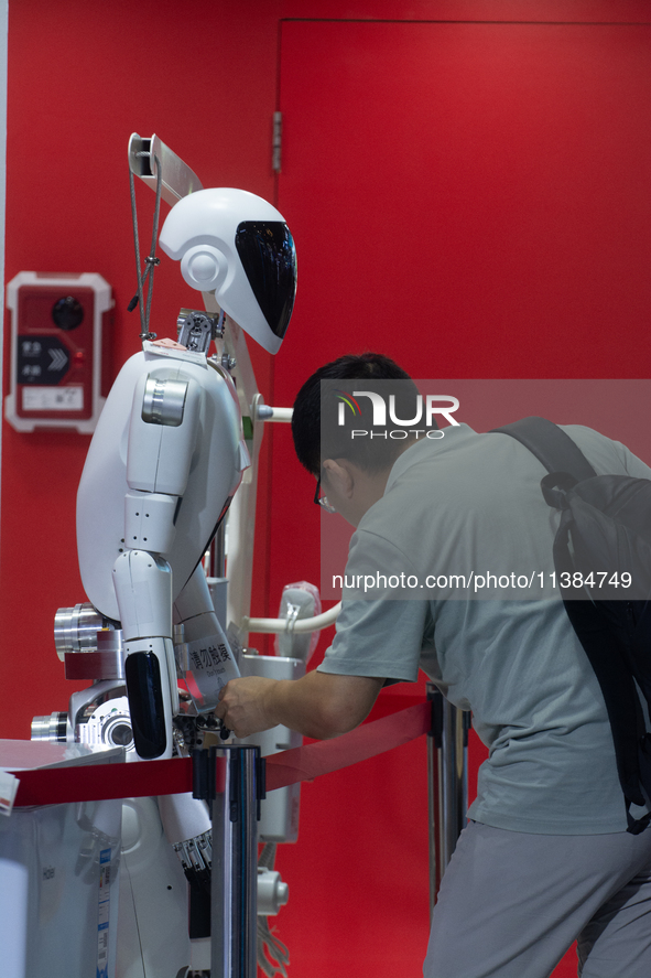 A visitor is interacting with a humanoid robot at the World Artificial Intelligence Conference at the Shanghai World Expo Exhibition Center...