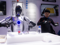 A humanoid robot is synchronizing a man's hand movement at the World Artificial Intelligence Conference at the Shanghai World Expo Exhibitio...