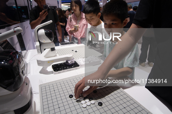 Visitors are playing chess games with robots at the World Artificial Intelligence Conference at the Shanghai World Expo Exhibition Center in...