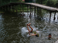 Kashmiri boys are taking a bath in the waters of Dal Lake to cool off on a hot summer day in Srinagar, Jammu And Kashmir, on July 05, 2024....