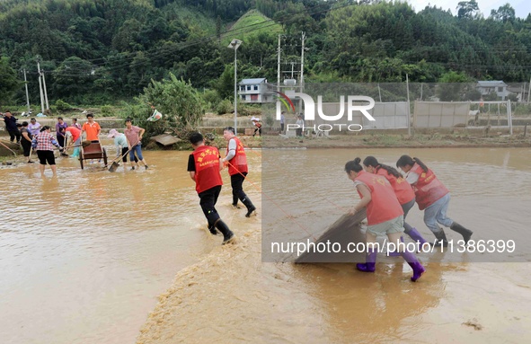 Volunteers are cleaning up silt in Si 'an village, Rongan county, Liuzhou city, South China's Guangxi Zhuang Autonomous region, in Liuzhou,...