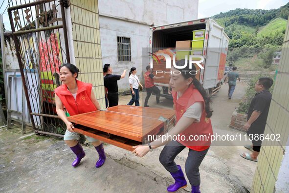 Young volunteers are moving a rollaway bed donated by an enterprise for a disaster-stricken villager in Si 'an Village, Rongan County, Liuzh...