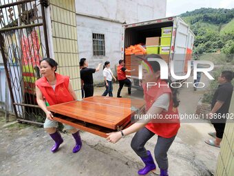 Young volunteers are moving a rollaway bed donated by an enterprise for a disaster-stricken villager in Si 'an Village, Rongan County, Liuzh...