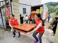 Young volunteers are moving a rollaway bed donated by an enterprise for a disaster-stricken villager in Si 'an Village, Rongan County, Liuzh...