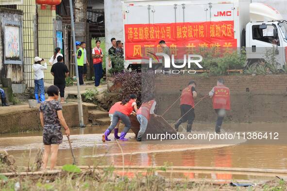 Volunteers are cleaning up silt in Si 'an village, Rongan county, Liuzhou city, South China's Guangxi Zhuang Autonomous region, in Liuzhou,...