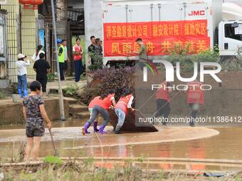 Volunteers are cleaning up silt in Si 'an village, Rongan county, Liuzhou city, South China's Guangxi Zhuang Autonomous region, in Liuzhou,...