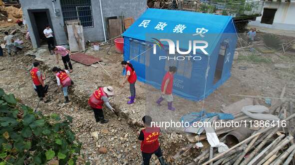 A worker is setting up tents for villagers in Si'an village, Rongan county, Liuzhou, China, on July 5, 2024. 