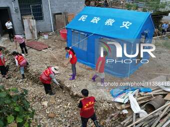 A worker is setting up tents for villagers in Si'an village, Rongan county, Liuzhou, China, on July 5, 2024. (