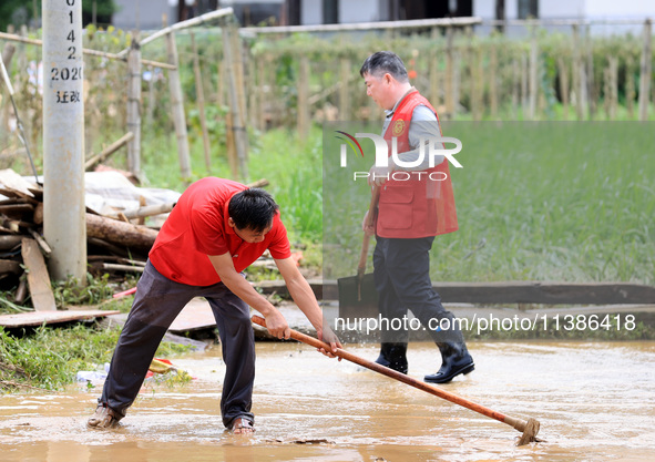 Volunteers are cleaning up silt in Si 'an village, Rongan county, Liuzhou city, South China's Guangxi Zhuang Autonomous region, in Liuzhou,...