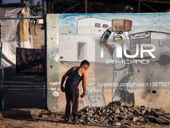 A displaced Palestinian is walking past the UNRWA Deir el-Balah distribution center, in Deir el-Balah in the central Gaza Strip, on July 6,...