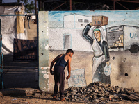 A displaced Palestinian is walking past the UNRWA Deir el-Balah distribution center, in Deir el-Balah in the central Gaza Strip, on July 6,...