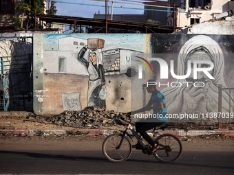 A Palestinian man is riding a bicycle past the UNRWA Deir el-Balah distribution center, in Deir el-Balah in the central Gaza Strip, on July...