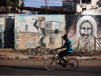 A Palestinian man is riding a bicycle past the UNRWA Deir el-Balah distribution center, in Deir el-Balah in the central Gaza Strip, on July...