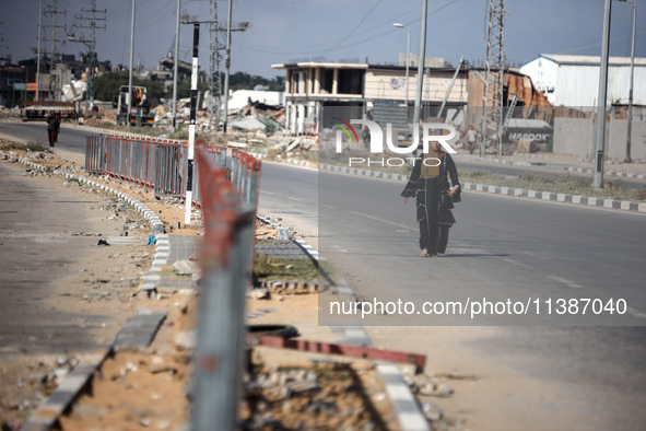 A displaced Palestinian woman is walking on Salah al-Din Street in Deir el-Balah in the central Gaza Strip on July 6, 2024, amid the ongoing...