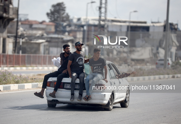 Palestinian men are sitting behind a car on Salah al-Din Street in Deir el-Balah in the central Gaza Strip on July 6, 2024, amid the ongoing...