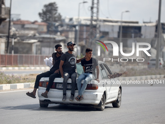 Palestinian men are sitting behind a car on Salah al-Din Street in Deir el-Balah in the central Gaza Strip on July 6, 2024, amid the ongoing...