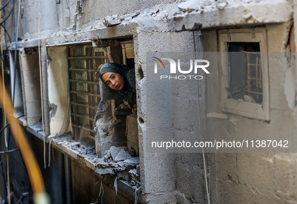 A Palestinian girl is looking out the window of a damaged apartment block following overnight Israeli strikes in Nuseirat refugee camp in th...