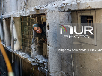 A Palestinian girl is looking out the window of a damaged apartment block following overnight Israeli strikes in Nuseirat refugee camp in th...