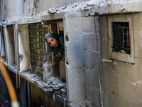 A Palestinian girl is looking out the window of a damaged apartment block following overnight Israeli strikes in Nuseirat refugee camp in th...