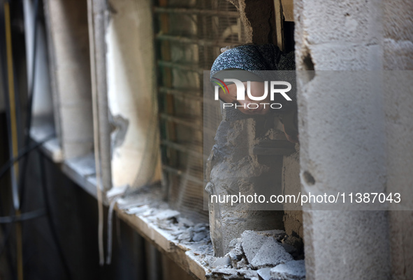 A Palestinian girl is looking out the window of a damaged apartment block following overnight Israeli strikes in Nuseirat refugee camp in th...