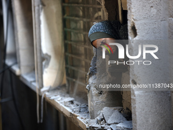 A Palestinian girl is looking out the window of a damaged apartment block following overnight Israeli strikes in Nuseirat refugee camp in th...