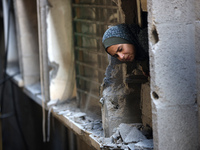 A Palestinian girl is looking out the window of a damaged apartment block following overnight Israeli strikes in Nuseirat refugee camp in th...