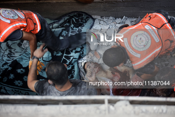 Palestinian civil defense staff are bringing out the body of a man after he was pulled out from under the rubble of a destroyed house after...