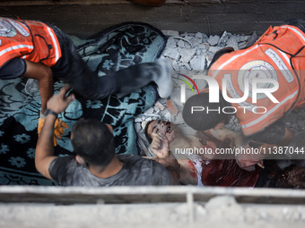 Palestinian civil defense staff are bringing out the body of a man after he was pulled out from under the rubble of a destroyed house after...