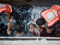 Palestinian civil defense staff are bringing out the body of a man after he was pulled out from under the rubble of a destroyed house after...