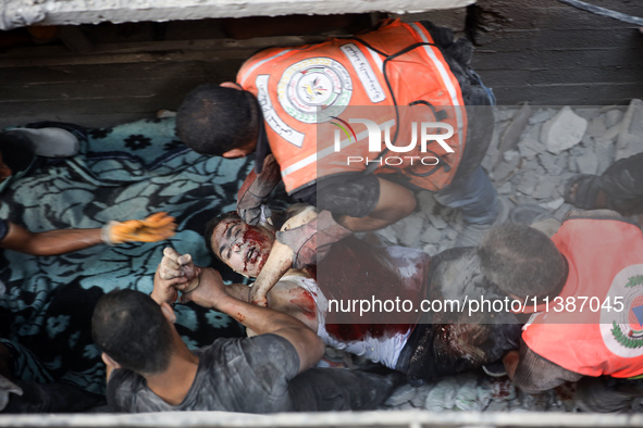 Palestinian civil defense staff are bringing out the body of a man after he was pulled out from under the rubble of a destroyed house after...