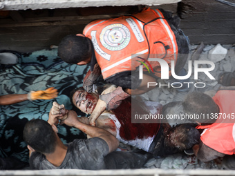 Palestinian civil defense staff are bringing out the body of a man after he was pulled out from under the rubble of a destroyed house after...