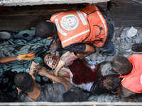 Palestinian civil defense staff are bringing out the body of a man after he was pulled out from under the rubble of a destroyed house after...