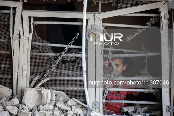 A Palestinian girl is looking out the window of a damaged apartment block following overnight Israeli strikes in Nuseirat refugee camp in th...