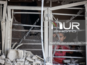 A Palestinian girl is looking out the window of a damaged apartment block following overnight Israeli strikes in Nuseirat refugee camp in th...